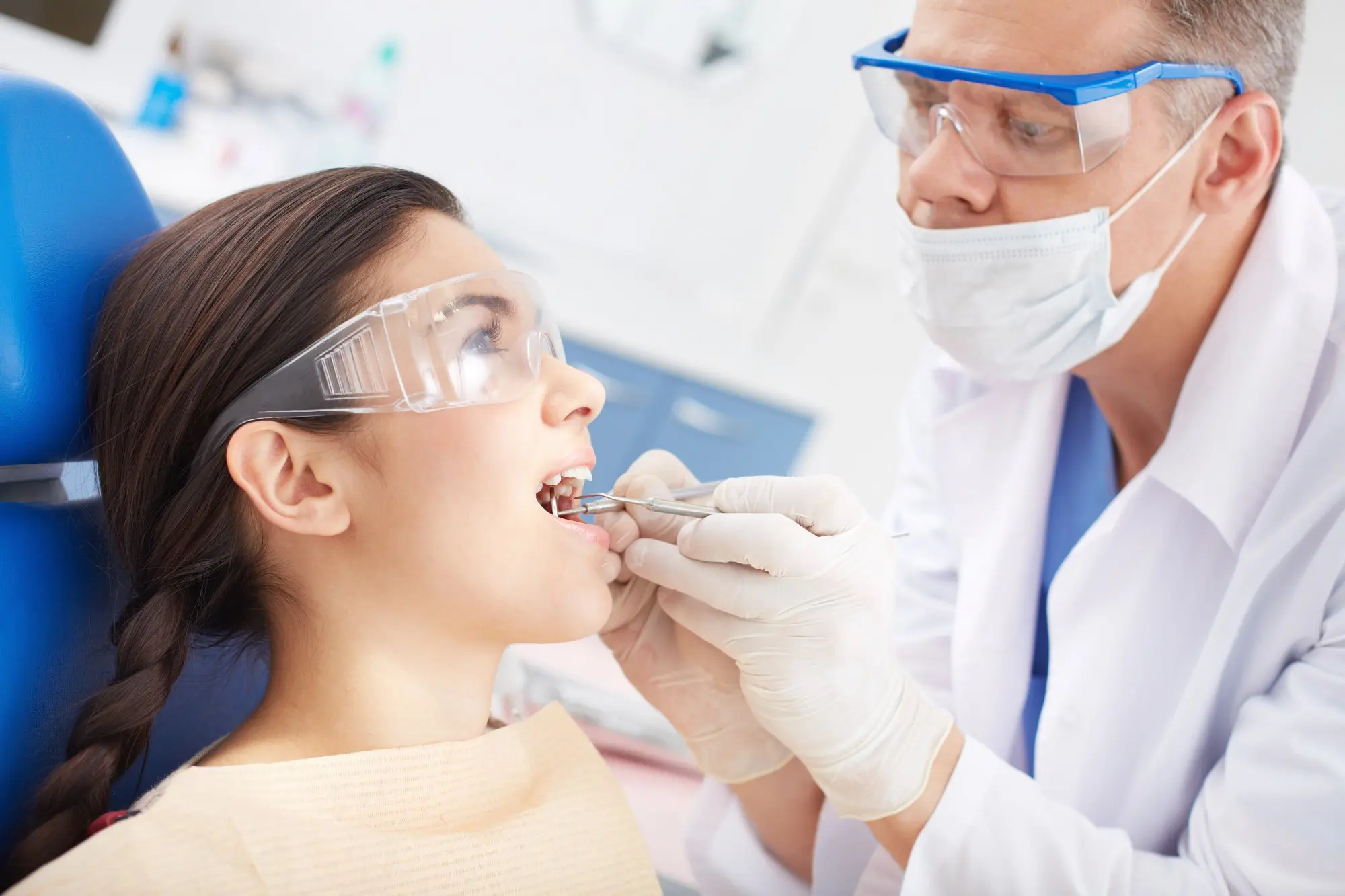 Orthodontist in protective gear examines a patient's underbite with dental tools at Redemption Orthodontics in Tallahassee, FL