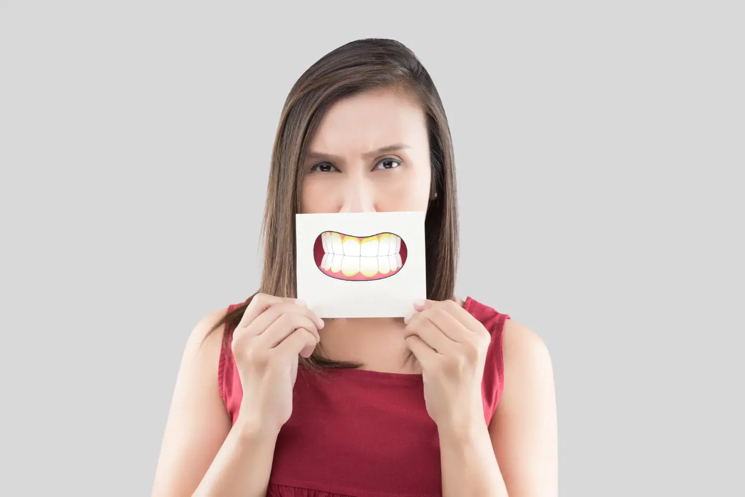 Woman holding a paper with a teeth image in front of her face for illustration underbite problem teeth at Redemption Orthodontics in Tallahassee, FL