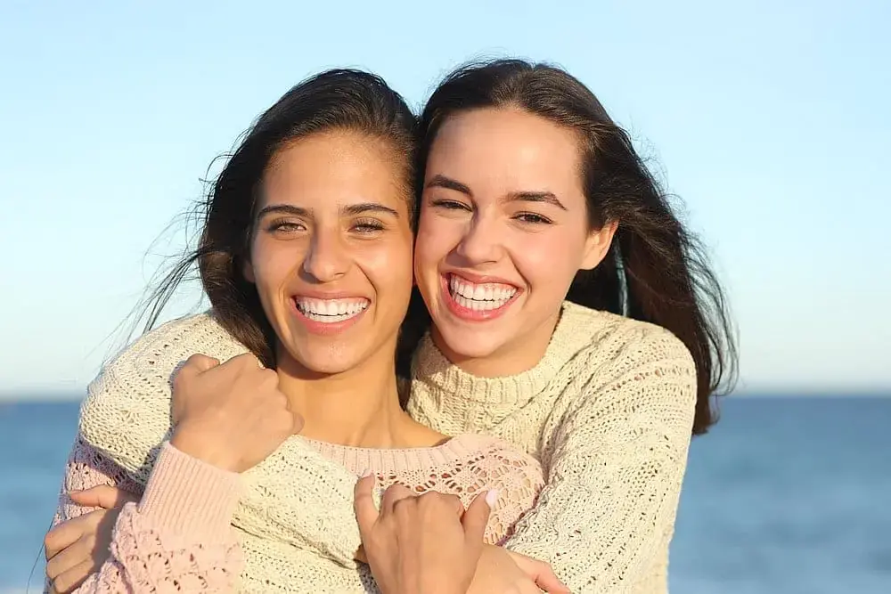 Smiling and hugging by the ocean, two young women enjoy the view , discussing about Braces vs Invisalign at Redemption Orthodontics in Tallahassee, FL. Smiling and hugging by the ocean, two young women enjoy the view , discussing about Braces vs Invisalign at Redemption Orthodontics in Tallahassee, FL.