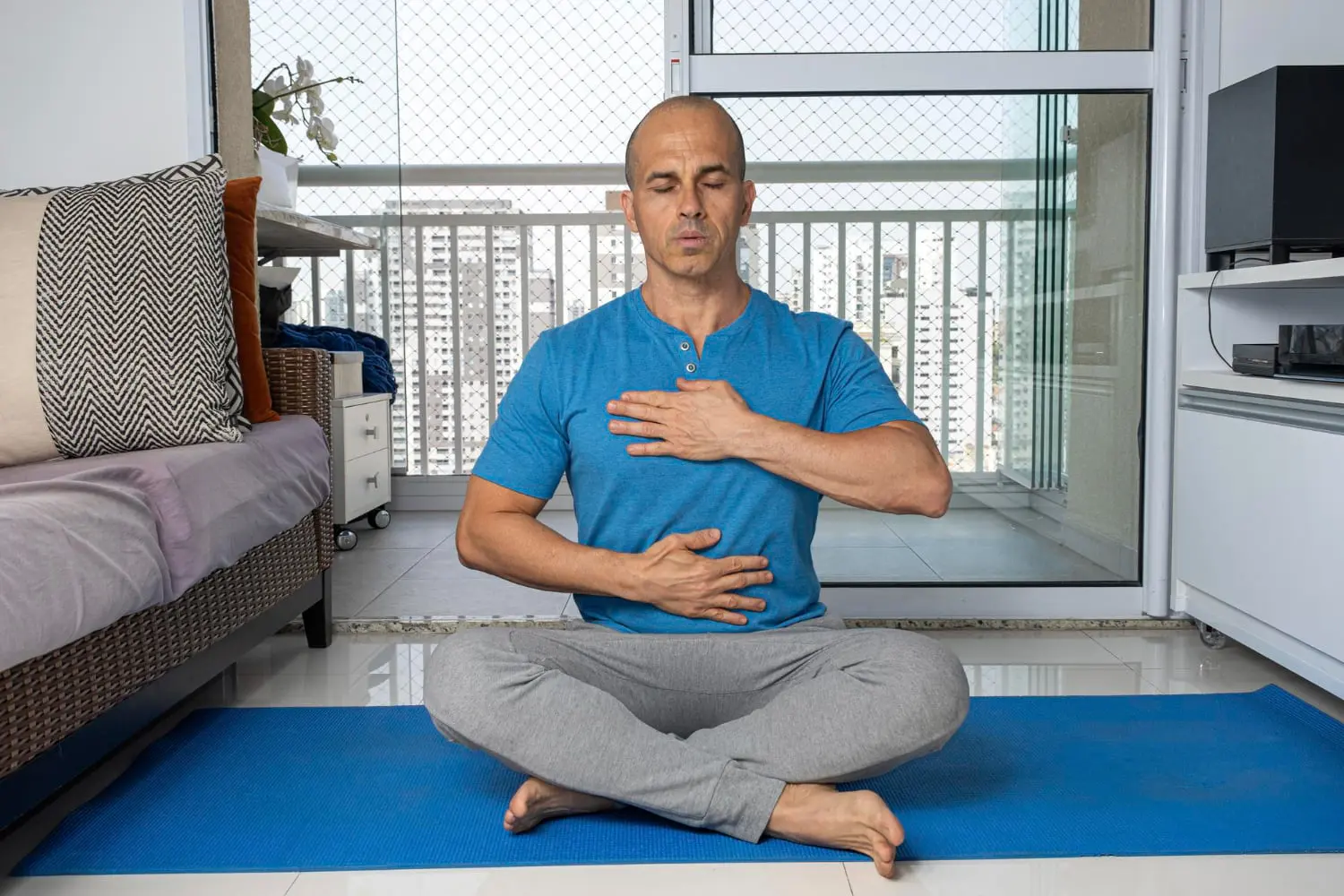 At Redemption Orthodontics in Tallahassee, FL, a man does prevention and management for mouth Breathing on a yoga mat, hands on chest and abdomen.