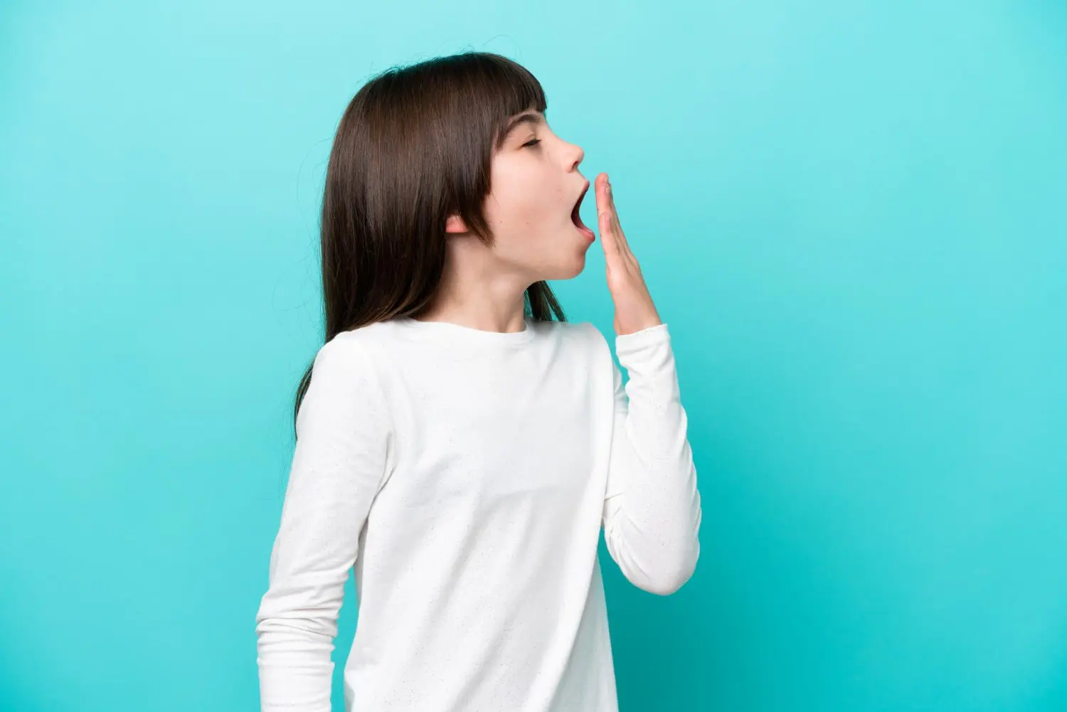 A young girl yawning and covering her mouth, highlighting causes of mouth breathing at Redemption Orthodontics in Tallahassee, FL.