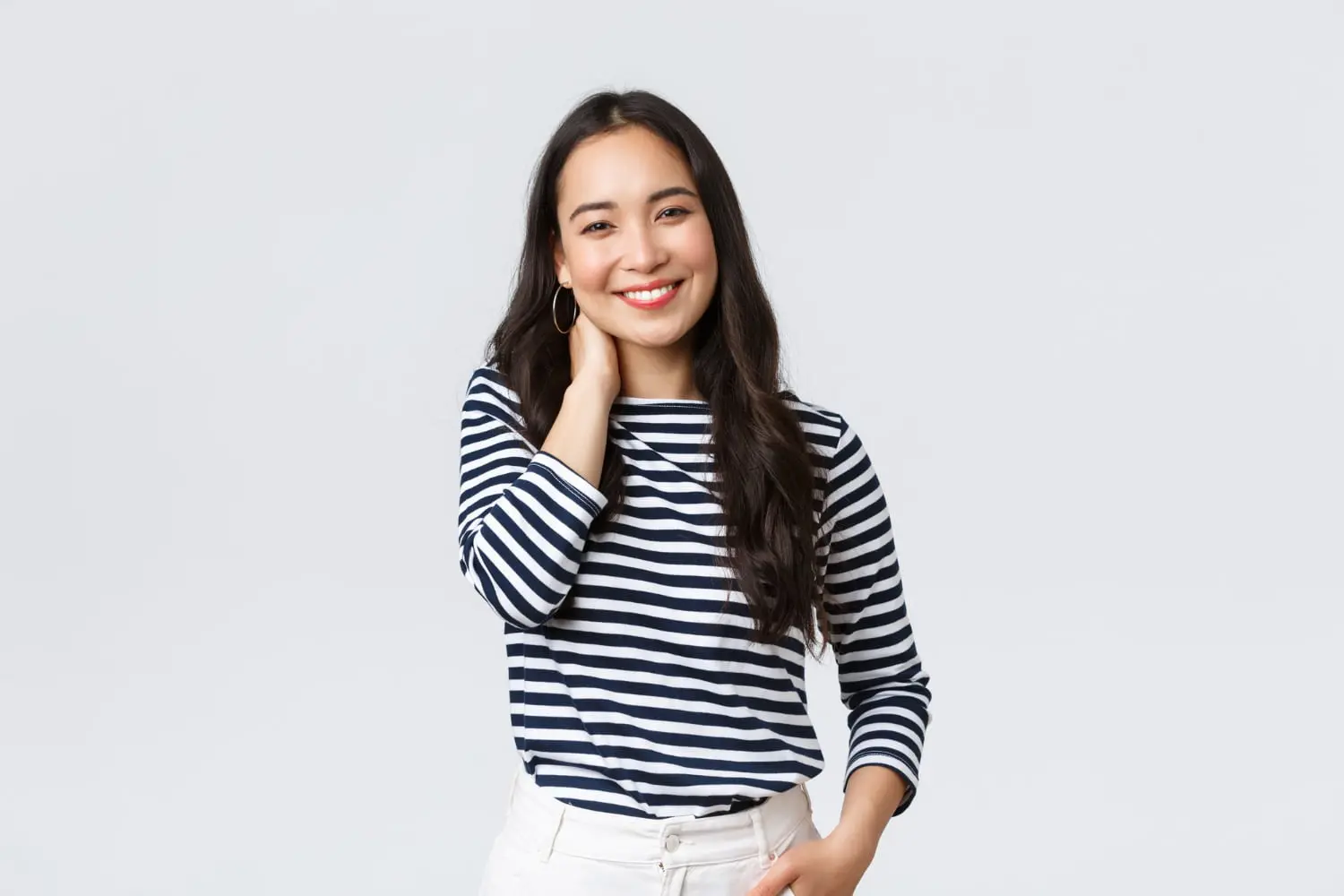 Confident woman in striped shirt and white pants smiles, showing Invisalign from Redemption Orthodontics in Tallahassee, FL.